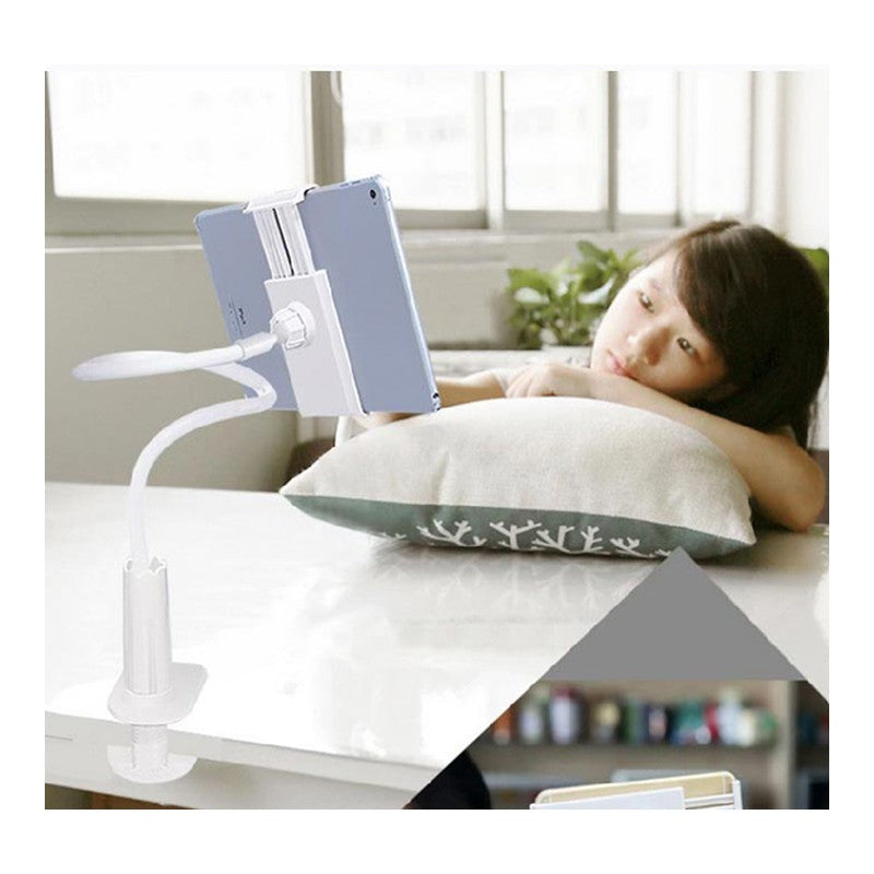 Child lying on a pillow with a tablet holder above, in a room with a window and plants.