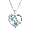 Heart-shaped pendant with turtle design and blue gemstones on a white background