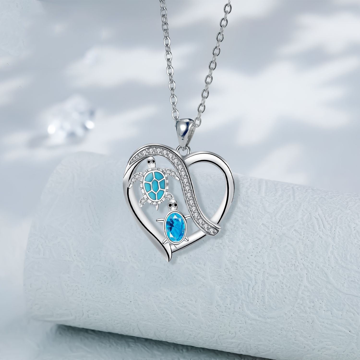 Heart-shaped silver necklace with blue gemstones on a white background